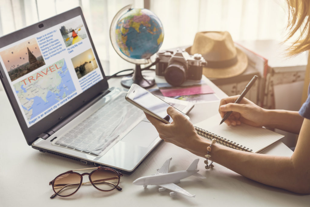 Young women planning vacation trip and searching information or booking an hotel on a smart phone and laptop, travel planning, planning on a budget