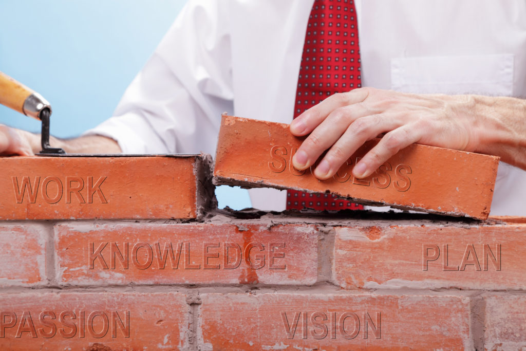 Businessman building a wall with bricks that have differents concepts printed on them. Concept for building a business or project.